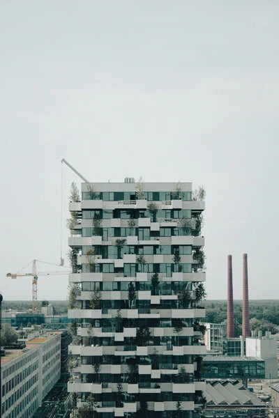 The Trudo Tower in Eindhoven, a modern apartment building with a 'vertical forest' of trees and shrubs on its balconies, representing innovative architecture.