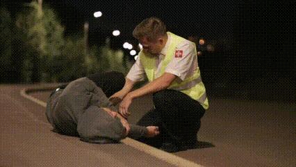Two medical personnel are urgently treating an injured cyclist.