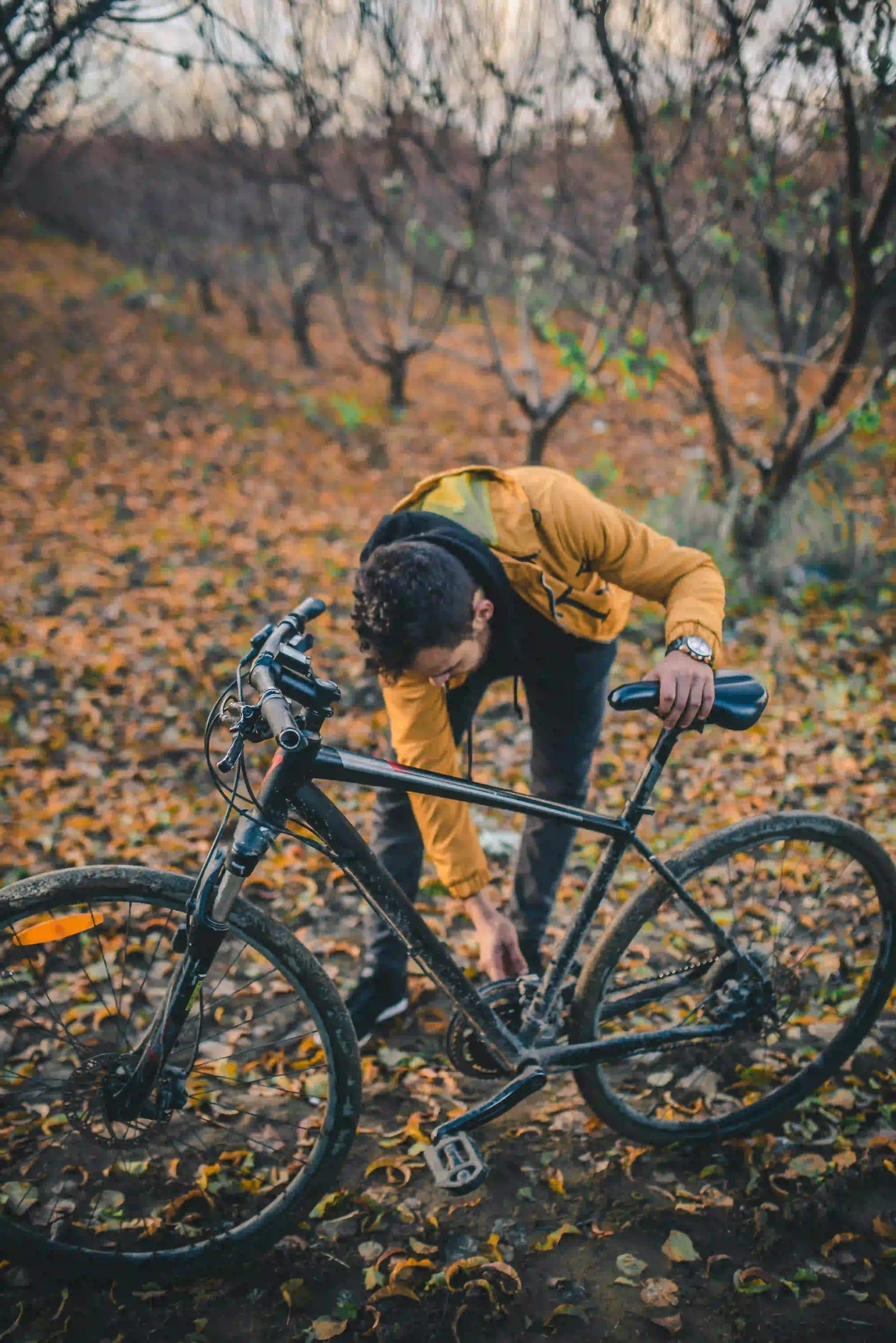 Cyclist outdoors checking the chain and drivetrain of a black bicycle
