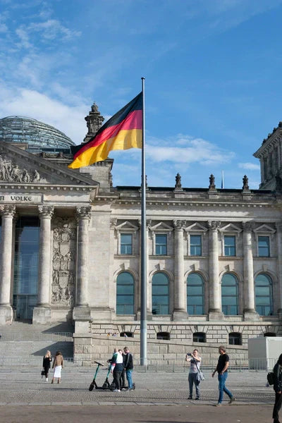The German flag waves in the breeze before the historic Reichstag Building in Berlin, the seat of the German parliament.