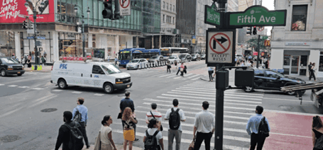 Busy New York City street crossing at Fifth Avenue with pedestrians waiting and cars passing